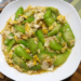 Plate of Cambodian luffa stir fried with scrambled eggs in light savory sauce on a wooden table, highlighting a simple Khmer home cooked meal.