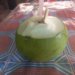 Fresh young green coconut with straw on patterned Khmer table on Phnom Chisor, Cambodia, highlighting affordable one dollar healthy coconut juice street drink.