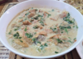Bowl of Cambodian kako tnaot soup with palm fruit, fish, and leafy greens in a creamy broth on a woven mat, traditional Khmer comfort food
