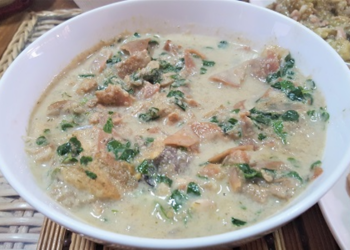 Bowl of Cambodian kako tnaot soup with palm fruit, fish, and leafy greens in a creamy broth on a woven mat, traditional Khmer comfort food