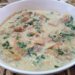 Bowl of Cambodian kako tnaot soup with palm fruit, fish, and leafy greens in a creamy broth on a woven mat, traditional Khmer comfort food