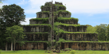 Stone pyramid temple of Prasat Thom at Koh Ker, Cambodia, seen from the front with steep central stairway and green vegetation covering its tiers.