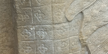Close view of an Preah Khan Apsara sandstone skirt showing grid based Kbach floral motifs that resemble elements of the modern Louis Vuitton monogram.