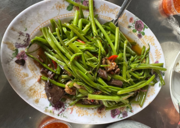 Stir-fried morning glory with chicken innards, chilies and garlic on a floral plate at a local eatery at Phnom Chisor temple in Takeo, Cambodia.