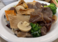 Plate of Buddha’s Delight vegetarian dish with tofu, mushrooms, broccoli, glass noodles, and mixed vegetables at Fisherman Quay restaurant in Phnom Penh, Cambodia.