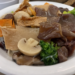 Plate of Buddha’s Delight vegetarian dish with tofu, mushrooms, broccoli, glass noodles, and mixed vegetables at Fisherman Quay restaurant in Phnom Penh, Cambodia.
