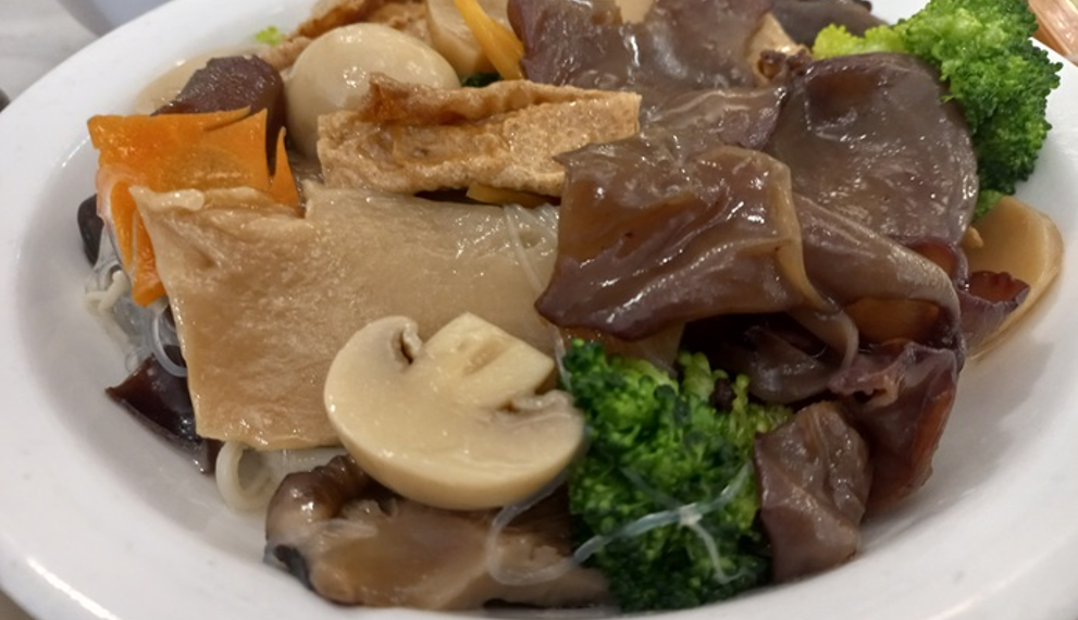 Plate of Buddha’s Delight vegetarian dish with tofu, mushrooms, broccoli, glass noodles, and mixed vegetables at Fisherman Quay restaurant in Phnom Penh, Cambodia.