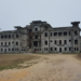 Bokor Palace before restoration on Bokor Hill, Cambodia, showing the abandoned colonial-era building with its weathered façade under an overcast sky.