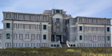 The restored Bokor Palace, a historic French colonial hotel in Bokor National Park, Cambodia, standing majestically against a blue sky.