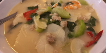 Traditional Cambodian bamboo shoot soup with bamboo shoots, shrimp, minced pork, leafy greens, and vegetables served in a light broth.