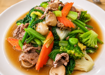 Sautéed vegetables with pork in a light savory sauce, a traditional Cambodian home-style dish featuring fresh greens, mushrooms, carrots, and broccoli.