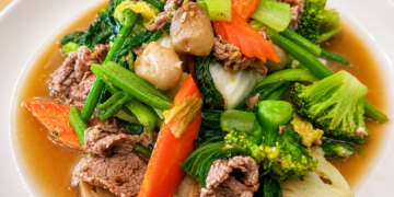 Sautéed vegetables with pork in a light savory sauce, a traditional Cambodian home-style dish featuring fresh greens, mushrooms, carrots, and broccoli.
