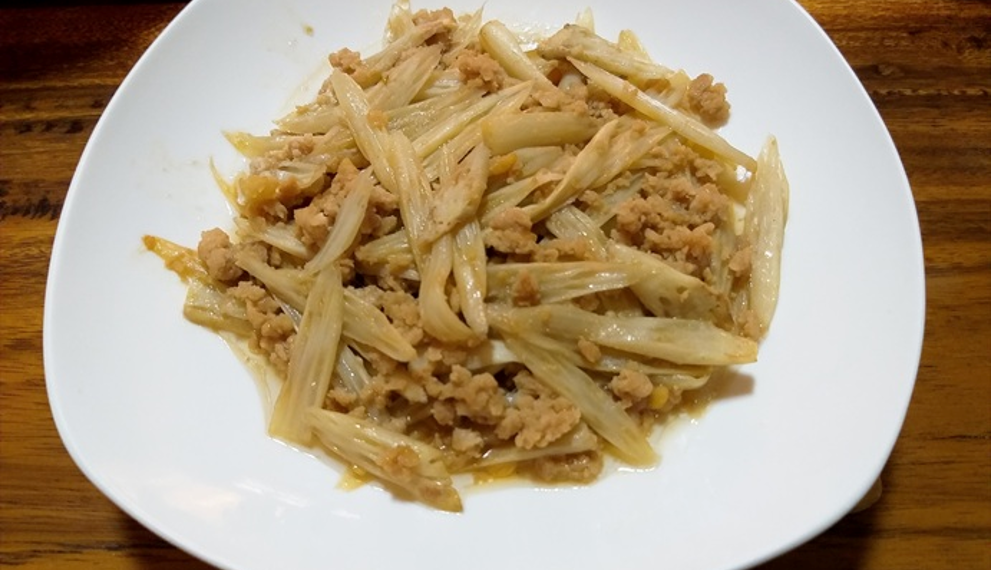 Cambodian stir-fried lotus stem with ground pork on a white plate over a wooden table
