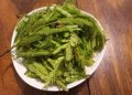 Fresh tamarind (Tamarindus indica) leaves arranged on a white plate, a traditional ingredient widely used in Khmer cuisine for soups and herbal dishes.