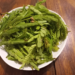 Fresh tamarind (Tamarindus indica) leaves arranged on a white plate, a traditional ingredient widely used in Khmer cuisine for soups and herbal dishes.