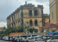 Old colonial-era commissariat building near Wat Phnom in Phnom Penh, Cambodia, with weathered yellow walls overlooking a busy street.