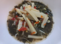 A bowl of Cambodian pickled bamboo shoots with African cabbage, chilies, bean sprouts, and herbs in a light brine.