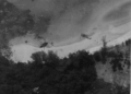 Two crashed U.S. Air Force CH-53 Sea Stallion helicopters lie damaged on the jungle-covered slopes of Koh Tang Island, Cambodia, during the Mayaguez Incident in May 1975. The black-and-white photograph captures the intense fighting that marked the final battle associated with the Vietnam War.