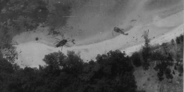 Two crashed U.S. Air Force CH-53 Sea Stallion helicopters lie damaged on the jungle-covered slopes of Koh Tang Island, Cambodia, during the Mayaguez Incident in May 1975. The black-and-white photograph captures the intense fighting that marked the final battle associated with the Vietnam War.