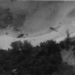Two crashed U.S. Air Force CH-53 Sea Stallion helicopters lie damaged on the jungle-covered slopes of Koh Tang Island, Cambodia, during the Mayaguez Incident in May 1975. The black-and-white photograph captures the intense fighting that marked the final battle associated with the Vietnam War.