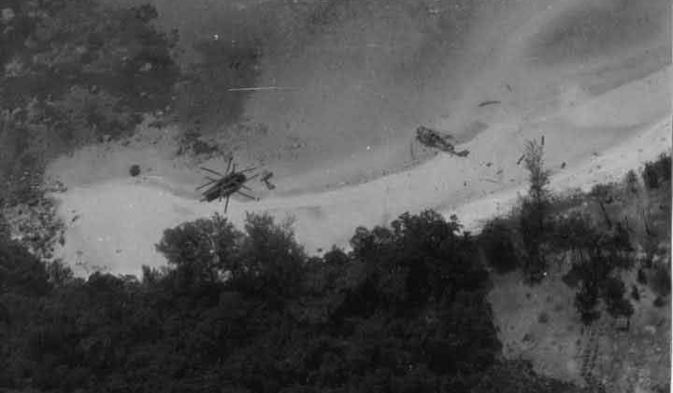 Two crashed U.S. Air Force CH-53 Sea Stallion helicopters lie damaged on the jungle-covered slopes of Koh Tang Island, Cambodia, during the Mayaguez Incident in May 1975. The black-and-white photograph captures the intense fighting that marked the final battle associated with the Vietnam War.