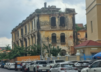 Old colonial-era commissariat building near Wat Phnom in Phnom Penh, Cambodia, with weathered yellow walls overlooking a busy street.