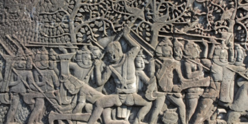 Bayon bas-relief showing Khmer warriors fighting Champa soldiers wearing distinctive helmets.