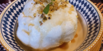 Floating island dessert with meringue, nuts, mint, and crème anglaise at La Ferme de Bassac Restaurant in Siem Reap, Cambodia.