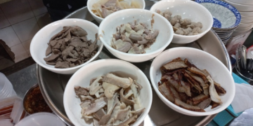 Bowls of meat, pork offal, meatballs, and other ingredients for បបរសាមចូក at Central Market in Phnom Penh, Cambodia