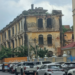 Old colonial-era commissariat building near Wat Phnom in Phnom Penh, Cambodia, with weathered yellow walls overlooking a busy street.