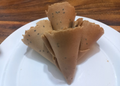 Golden Cambodian thâng muon wafers with black sesame seeds arranged on a white plate.