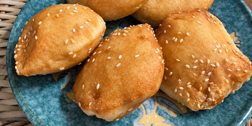 Cambodian sesame hollow doughnuts called នំប៉ោង on a blue plate in Phnom Penh