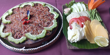 Grilled Cambodian prahok served with fresh raw vegetables, lime, and herbs at Neari Khmer Restaurant in Siem Reap.